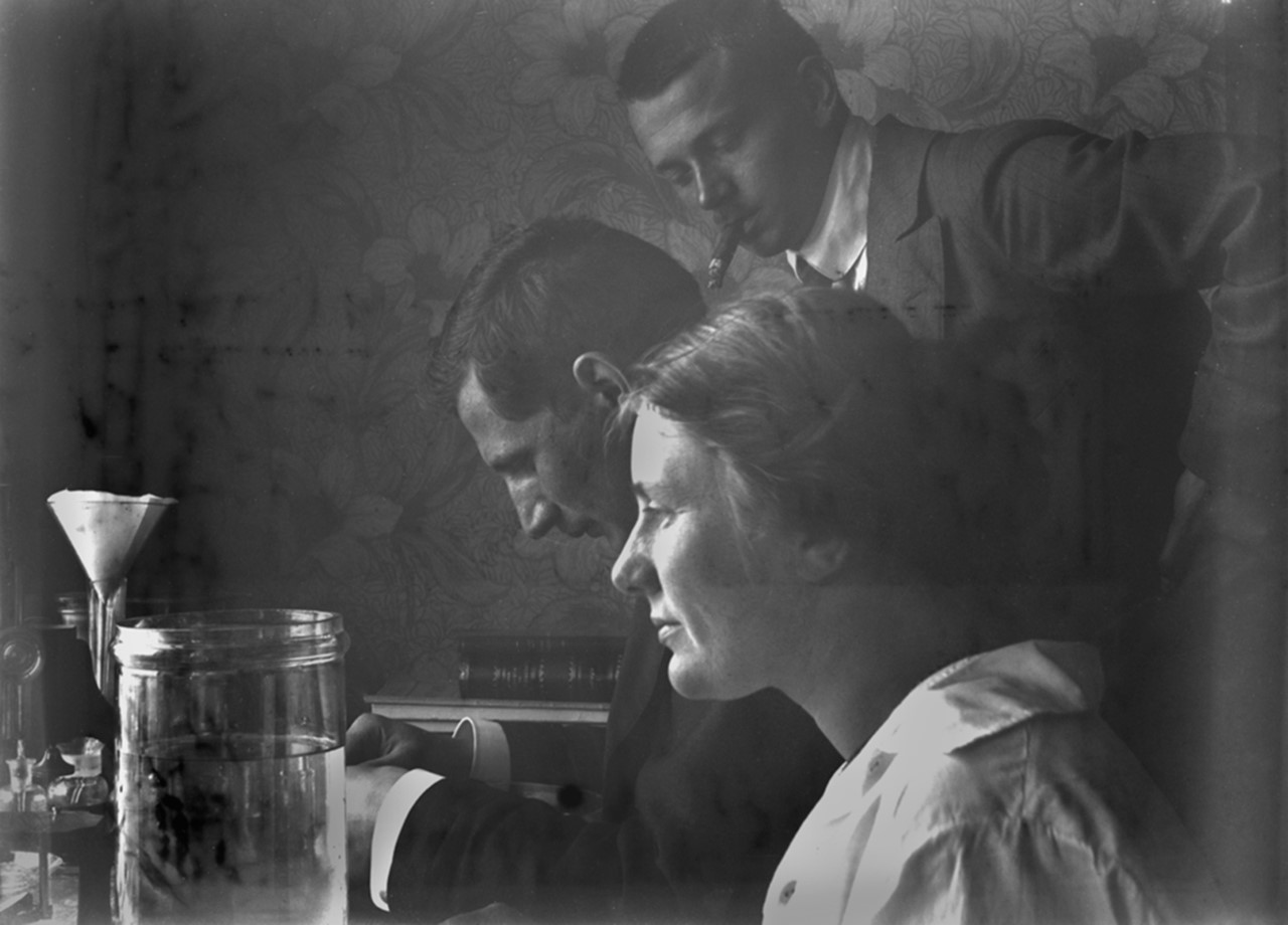 Elisabet Petersson vid arbetsbord med två icke namngivna män, Helgoland, 1913. Fotograf okänd, eventuellt självporträtt (Göteborgs naturhistoriska museums arkiv)